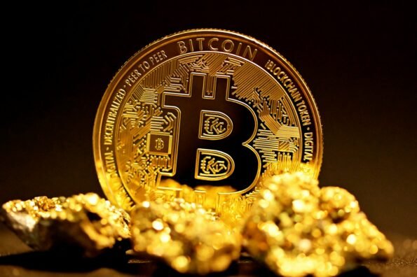 Moneda de bitcoin sobre pepitas de oro representando el repunte de precio por encima de los $78,000